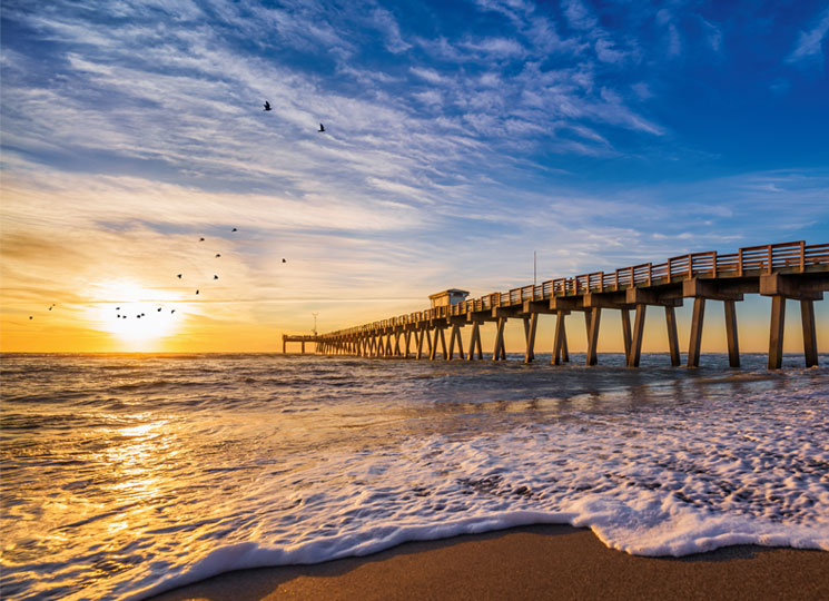 Boardwalk reaching out into the ocean with a sunset