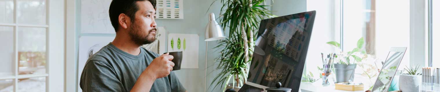 Home business person drinking coffee looking at computer.