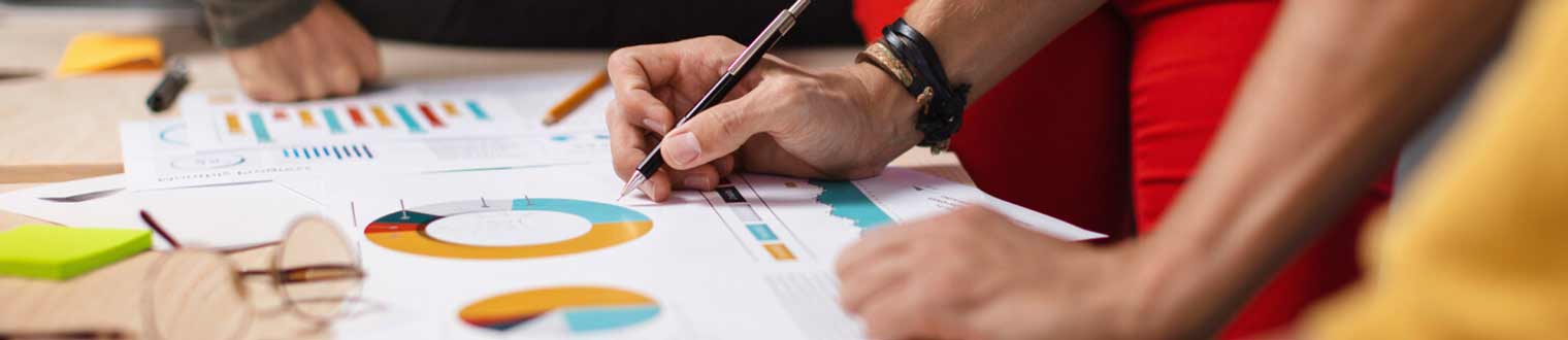 Man holding pen over spreadsheets