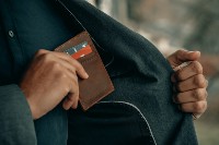Man with wallet putting it in coat pocket