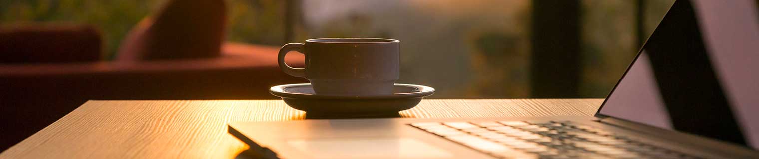 Cup of coffee next to a laptop.