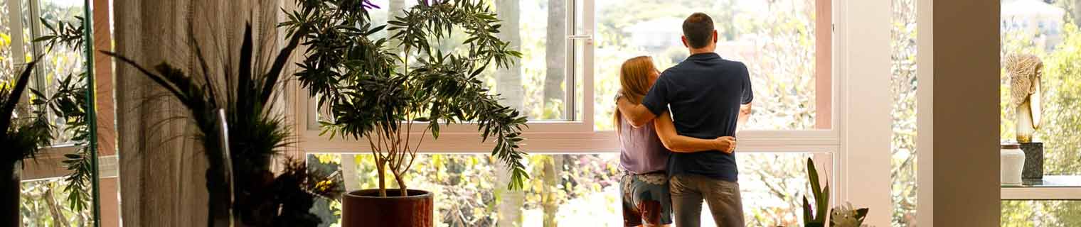 Couple looking out the window of their home.