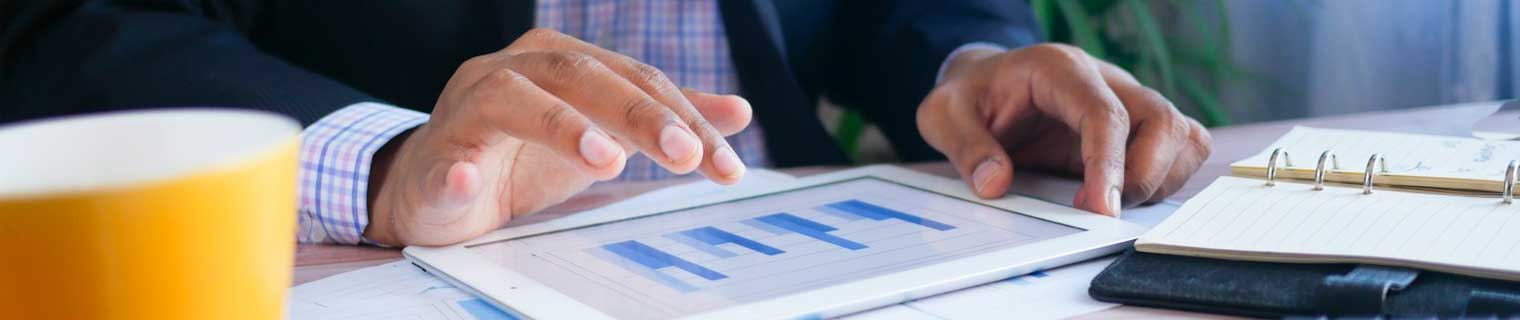 Business person using tablet looking at financial graph.